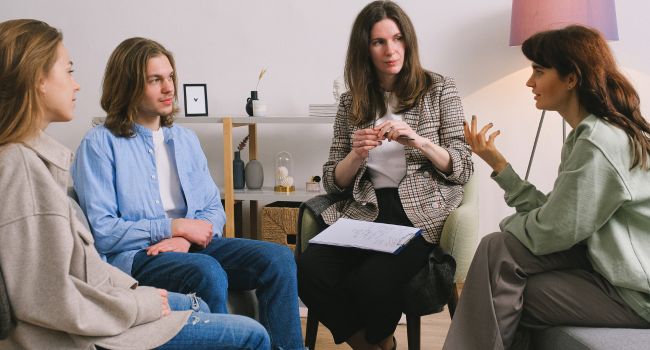 Teens and therapist engaged in a group discussion, representing the supportive environment of teen group therapy, helping parents consider if this setting is right for their child’s mental health needs.
