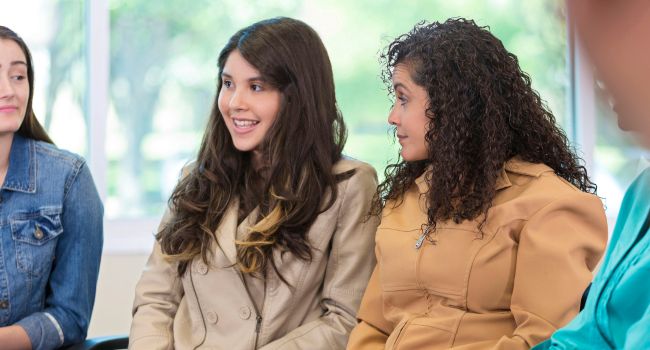 Teens engaging in group therapy, sharing and listening to each other. This environment fosters emotional support, builds communication skills, and helps with personal growth and healing.