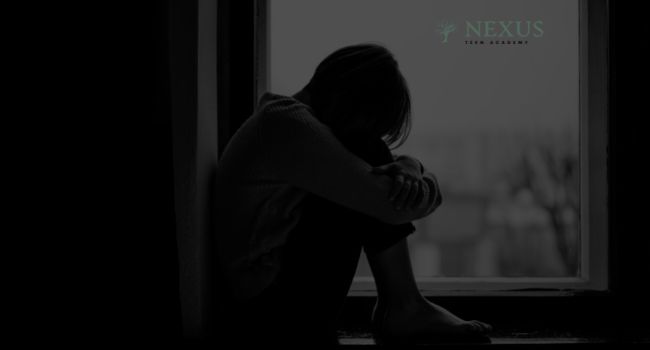 A teenager sitting alone by a window in a dimly lit room, representing the emotional and psychological struggles tied to isolation and the common reasons teens in Arizona stay in their rooms.