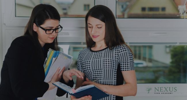 Two women review files together in an office setting, symbolizing collaboration and organization within Arizona's Juvenile Residential Placement system to provide structure and support for youth.