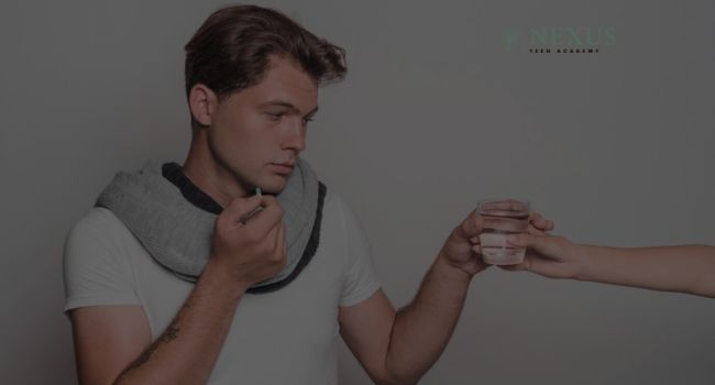 A concerned teenage boy holding medication while accepting a glass of water, reflecting the complexities of understanding drug dealing and its emotional toll among teenage boys in Arizona.