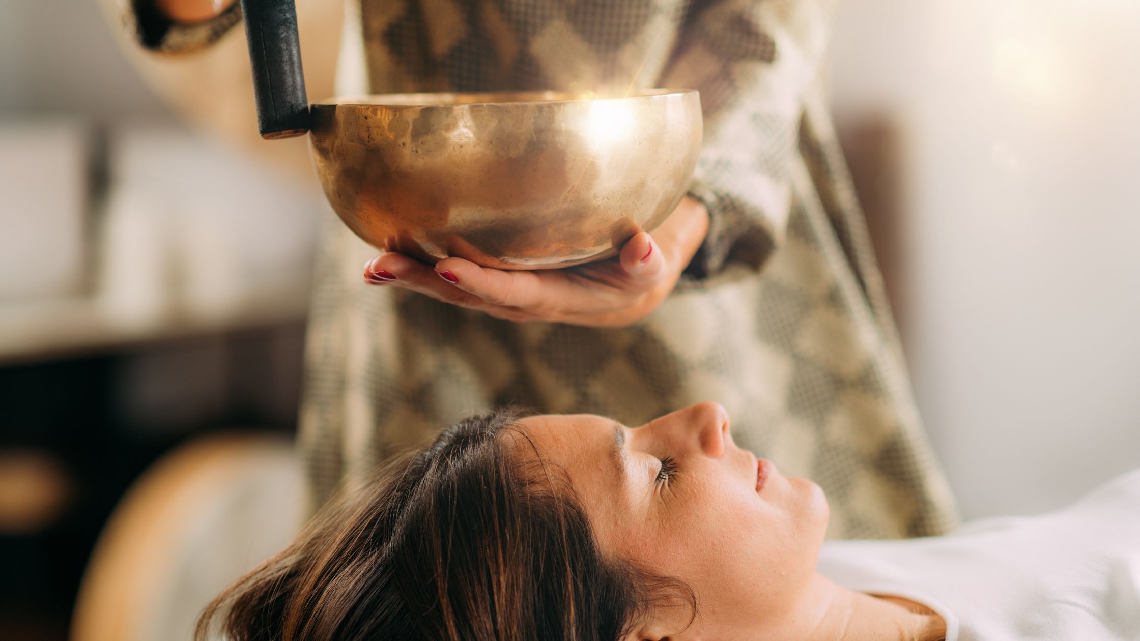 A teen experiencing sound healing therapy with a singing bowl, promoting relaxation, stress relief, and emotional well-being through soothing vibrations.