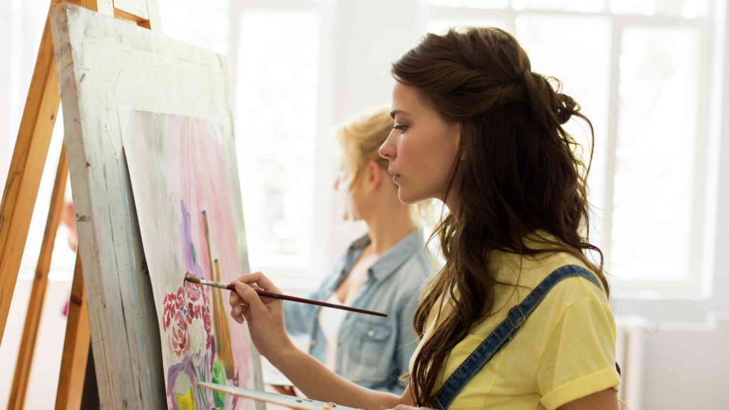 Teen girl painting on a canvas during an art therapy session, using creativity as a tool for emotional expression and mental well-being in a therapeutic setting.