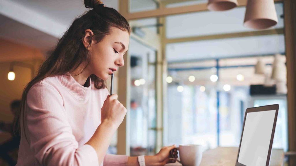 Teen girl in deep thought while journaling on a laptop, representing common techniques used in trauma-focused therapy to help teens process and heal from past experiences.