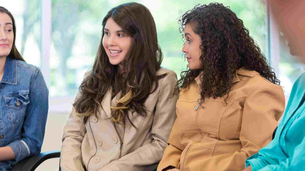 Teen girls engaged in a supportive group therapy session, representing how trauma-focused therapy techniques help teens build resilience, trust, and emotional healing.