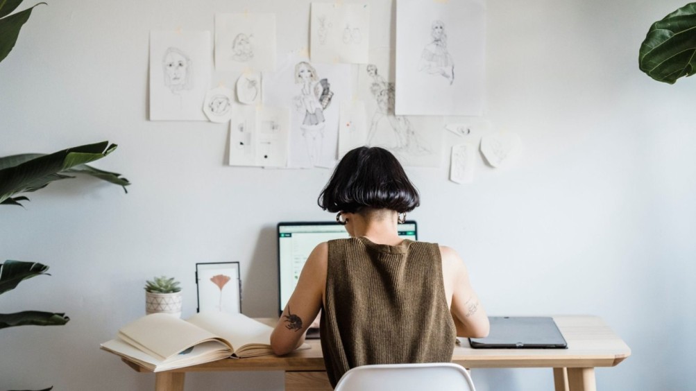 A person working at a desk with art sketches on the wall, symbolizing self-expression. Represents how trauma-focused therapy fosters healing.
