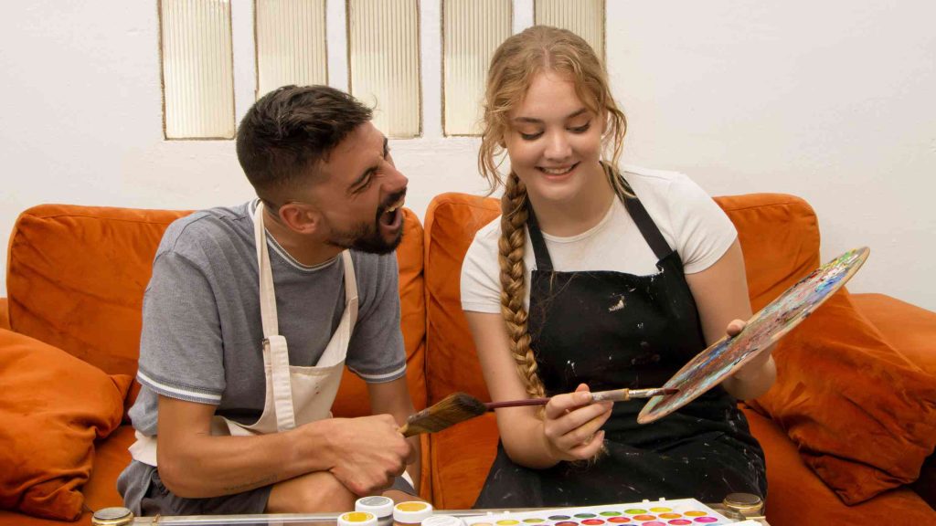 Two teens engaged in a joyful art therapy session, painting together with bright colors, illustrating how to get started with teen art therapy in a fun and supportive way.