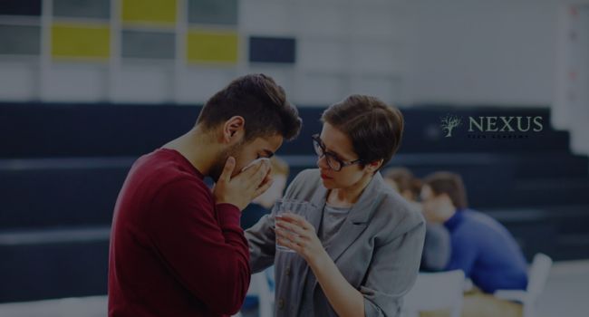 A concerned mentor offers water to a distressed teen in a school setting. Implementing anger management for teens helps build emotional resilience, self-control, and healthy coping strategies for stress.