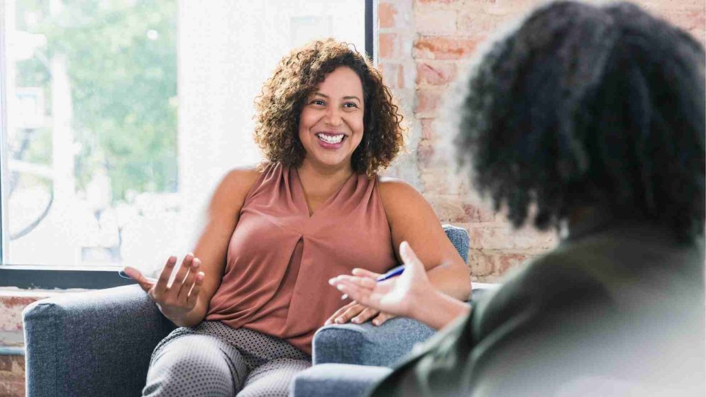 The image shows two people engaged in a conversation, representing the interpersonal aspect of exposure therapy, where clients discuss their fears and gradually face them in a controlled, supportive environment.