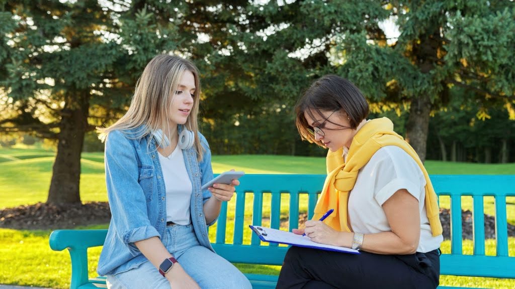 A counselor and a teen engage in a motivational interviewing session outdoors, using effective strategies to encourage self-reflection and goal setting in teens.