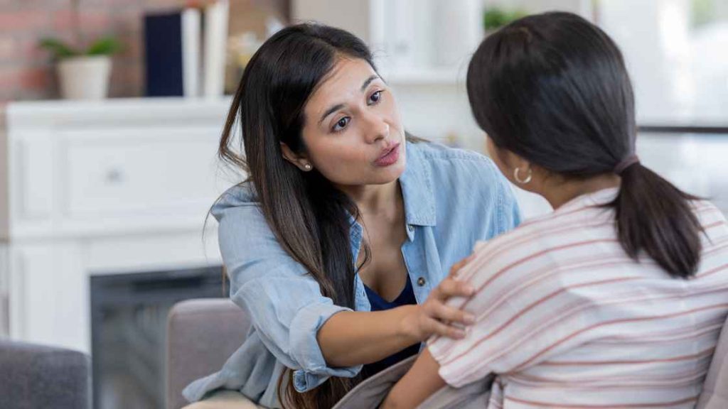 A concerned woman gently talks to and supports a young girl during an emotional moment, highlighting empathy and care – Nexus Teen Academy.