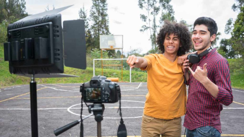Two happy teens recording content outdoors, highlighting the positive effects of social media on teen mental health.