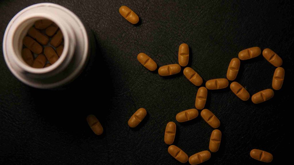 Open bottle with scattered brown stimulant medication pills on a dark surface, representing common ADHD treatments for teens.