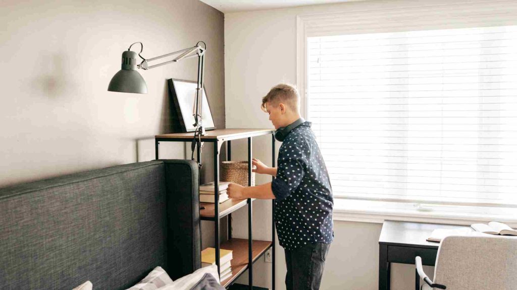 Teen organizing shelves neatly, representing compulsive behaviors as a physical sign of OCD in adolescents.