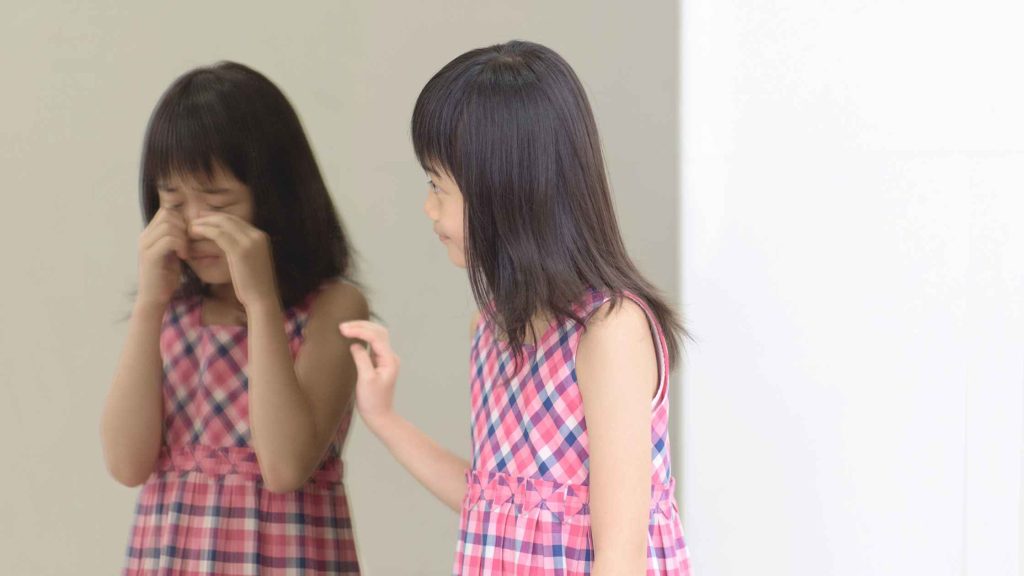 Young girl looking at her reflection, symbolizing how self-image forms in teens and impacts their self-perception.