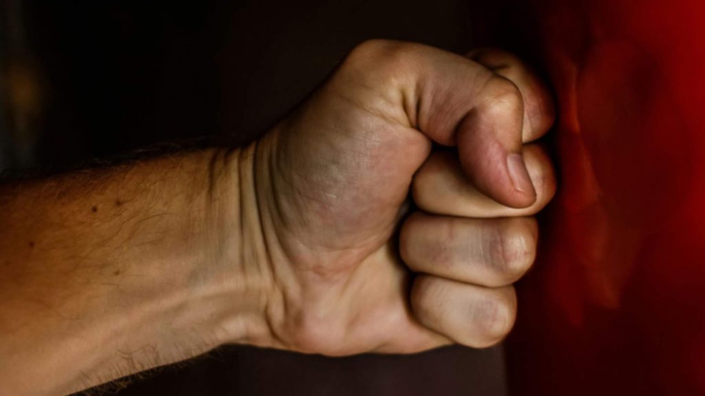 Close-up of a clenched fist symbolizing aggression and anger often associated with conduct disorder in teens.