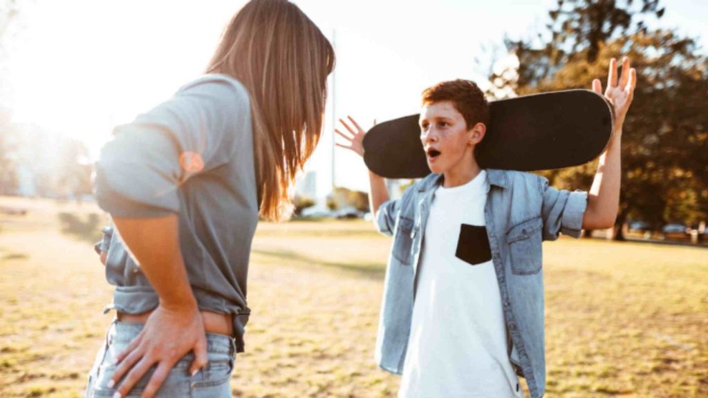Teen reacts defensively while holding a skateboard as a parent confronts him, echoing behavior that signals deeper concerns.