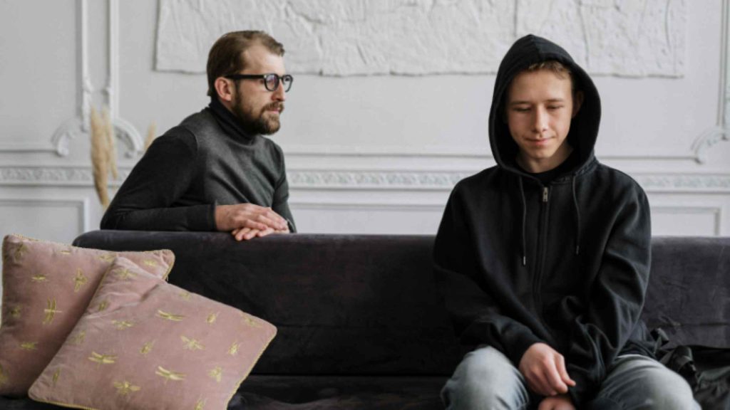 A father talks with his withdrawn teenage son, capturing the tension and care needed when addressing marijuana use.